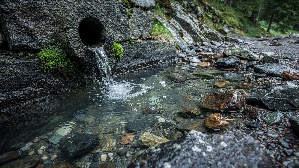 Mineral water running from a stone spring outlet into a shallow pool